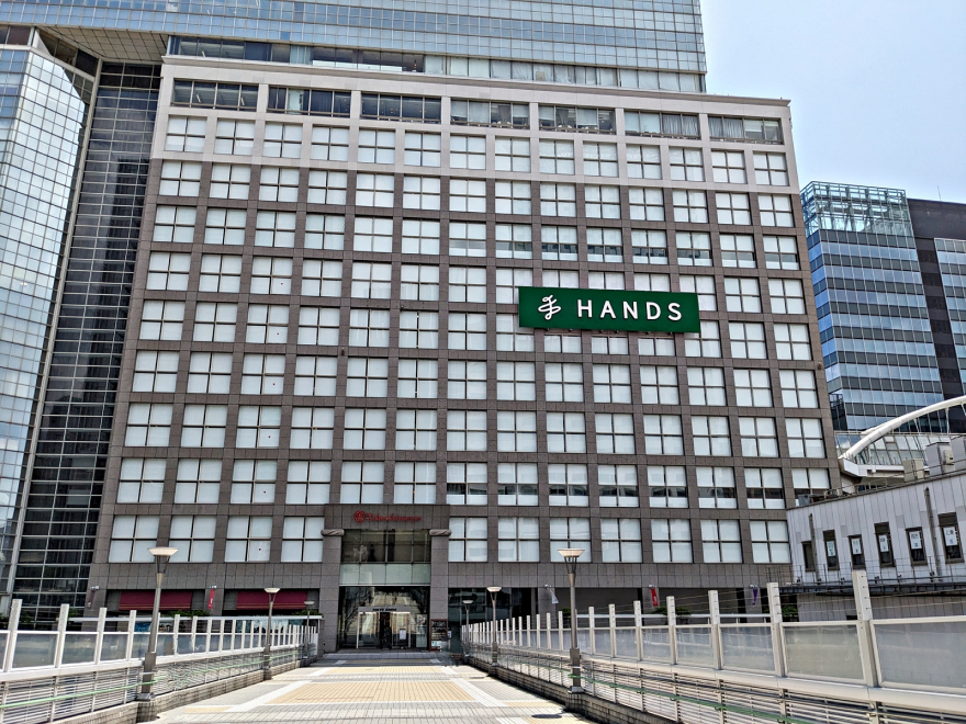 歩道橋から見た、緑の「HANDS」看板を掲げるハンズ新宿店の昼間の外観