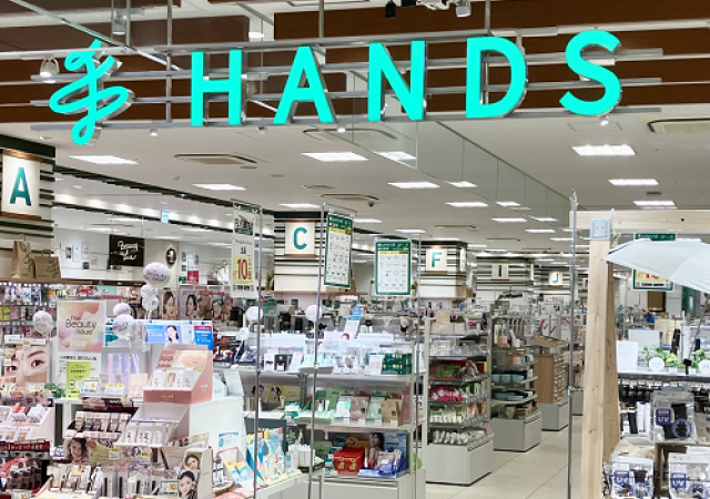 「HANDS」のロゴサインの下にコスメ売り場が広がる、ハンズ姫路店の店内